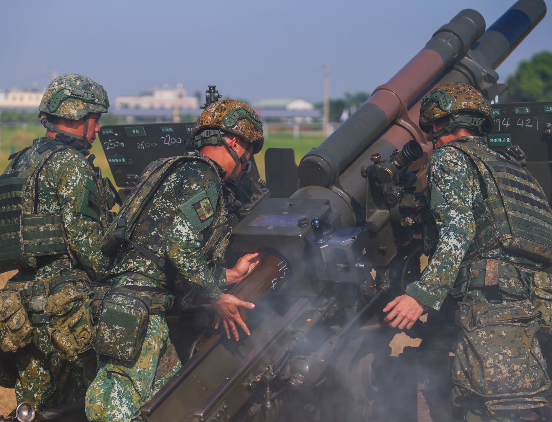  裝填手將砲彈推入砲膛，待命射擊。（記者連琳攝）