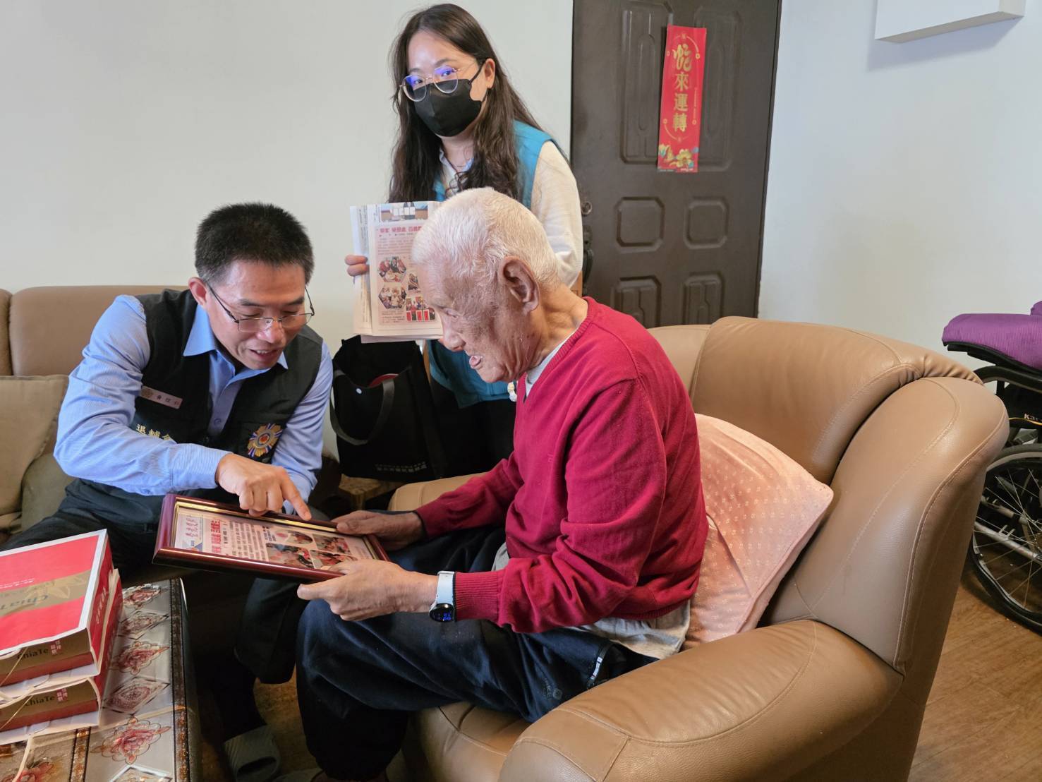 臺北市榮服處處長黃信仁請同仁們將榮光雙週刊百歲慶生專欄及青年日報的相關報導剪輯後精心裱框，親送曹爺爺家中，讓爺爺能珍藏這份專屬於他的榮耀時刻。（臺北市榮服處提供）