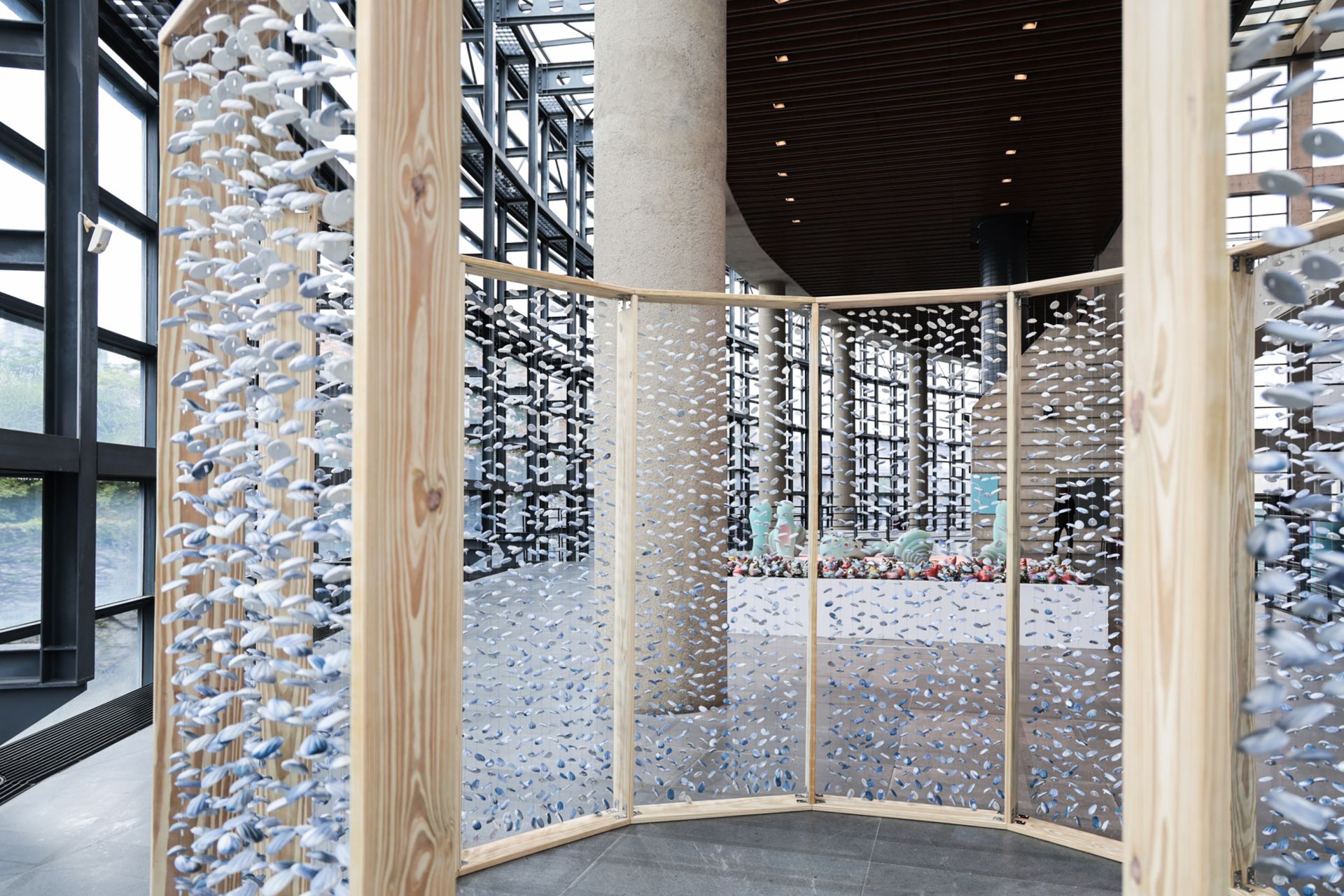 數千片藍白陶片如貝殼懸掛的裝置，觀眾可步入其間體驗被陶片環繞的庇護與歸屬感。（鶯歌陶博館提供）