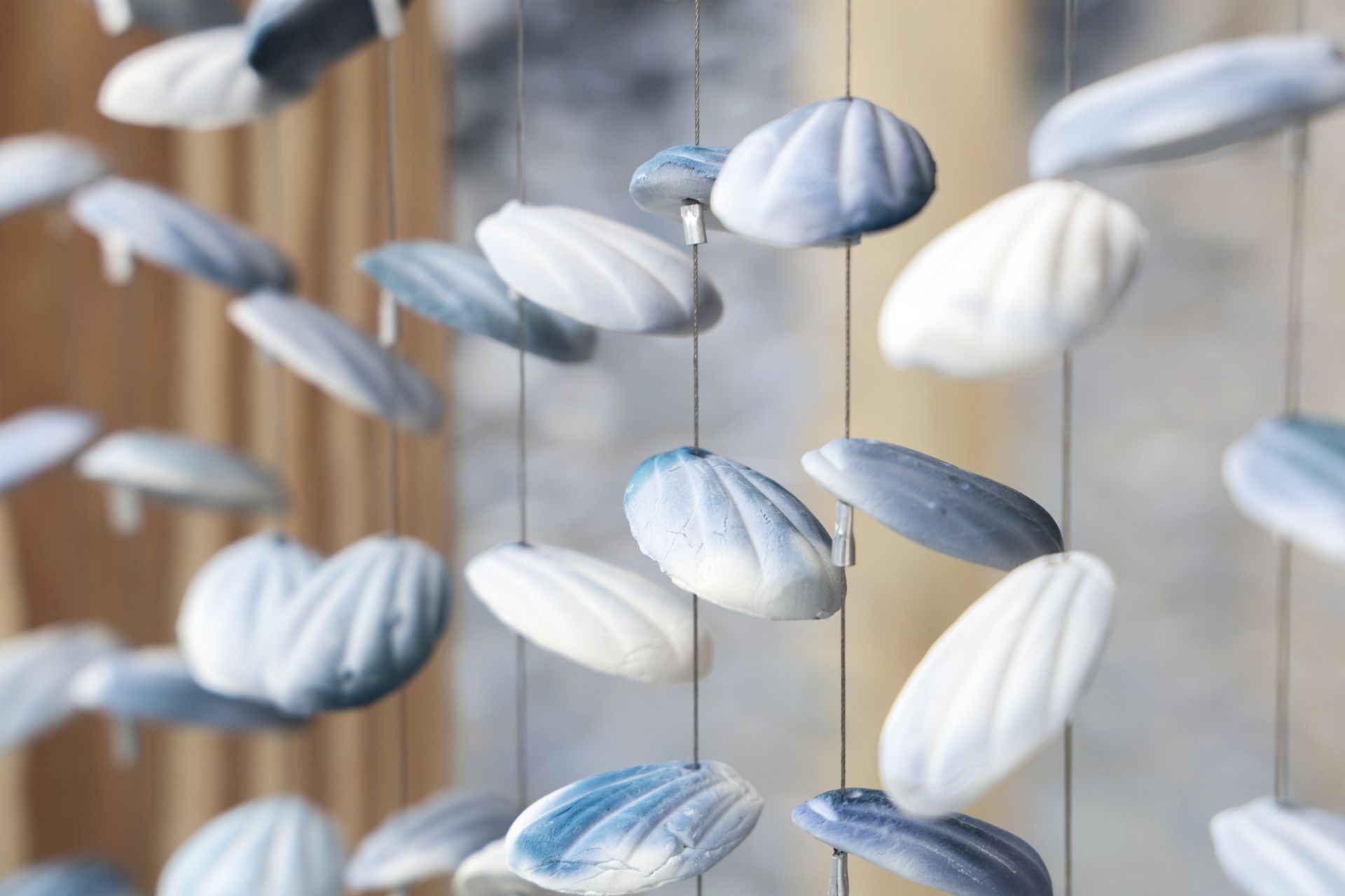 數千片藍白陶片如貝殼懸掛的裝置，觀眾可步入其間體驗被陶片環繞的庇護與歸屬感。（鶯歌陶博館提供）