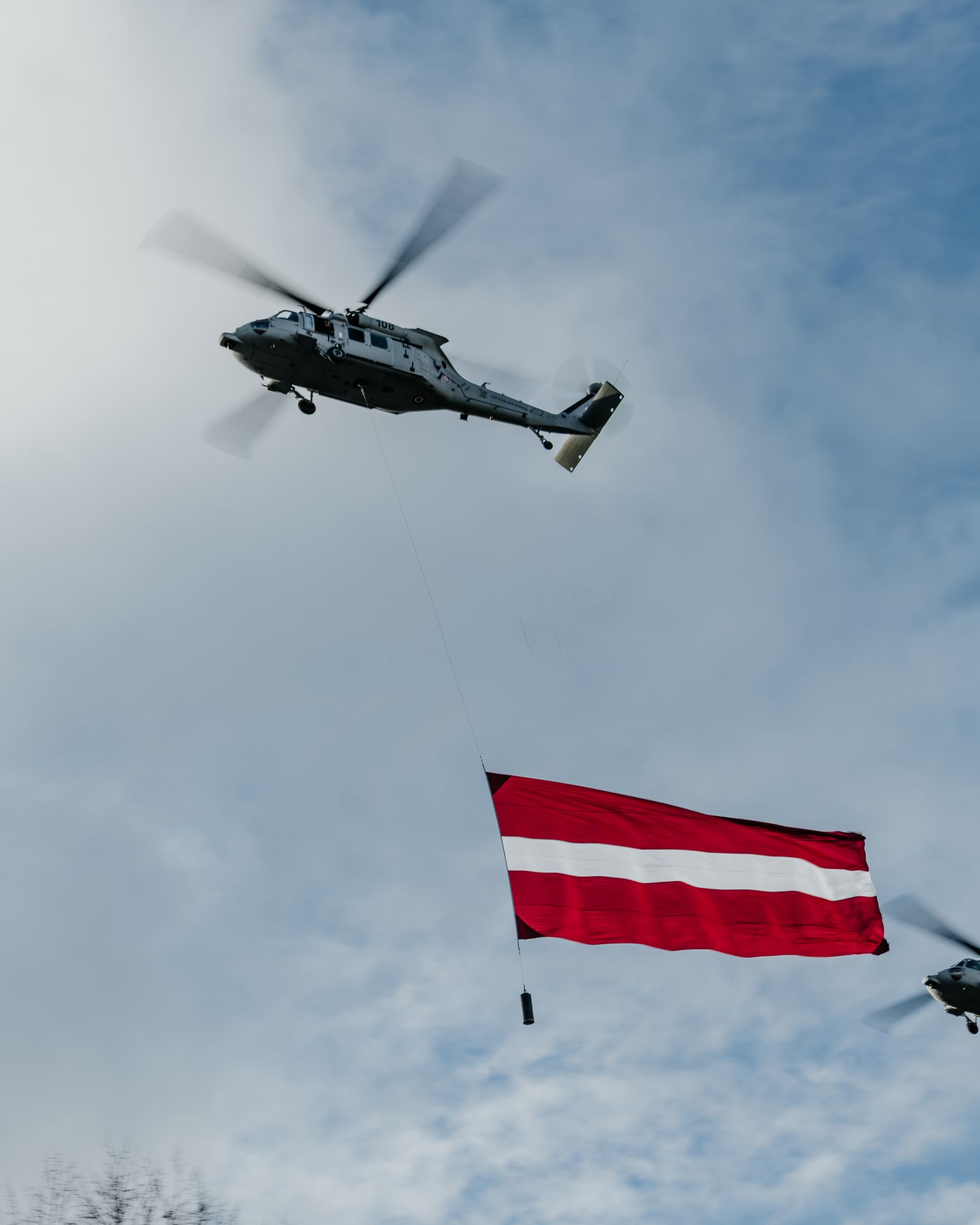  拉脫維亞空軍出動UH-60M「黑鷹」直升機懸掛巨幅國旗，飛越典禮上空。（取自拉脫維亞國防部Flickr）