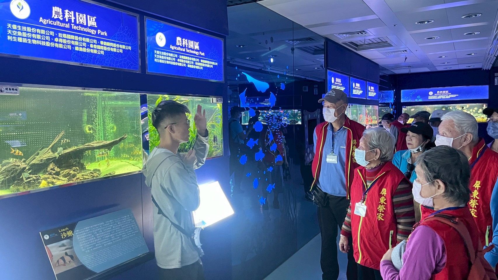 長輩們認真聆聽導覽人員的介紹，了解水族中的自然生態。（屏東榮家提供）