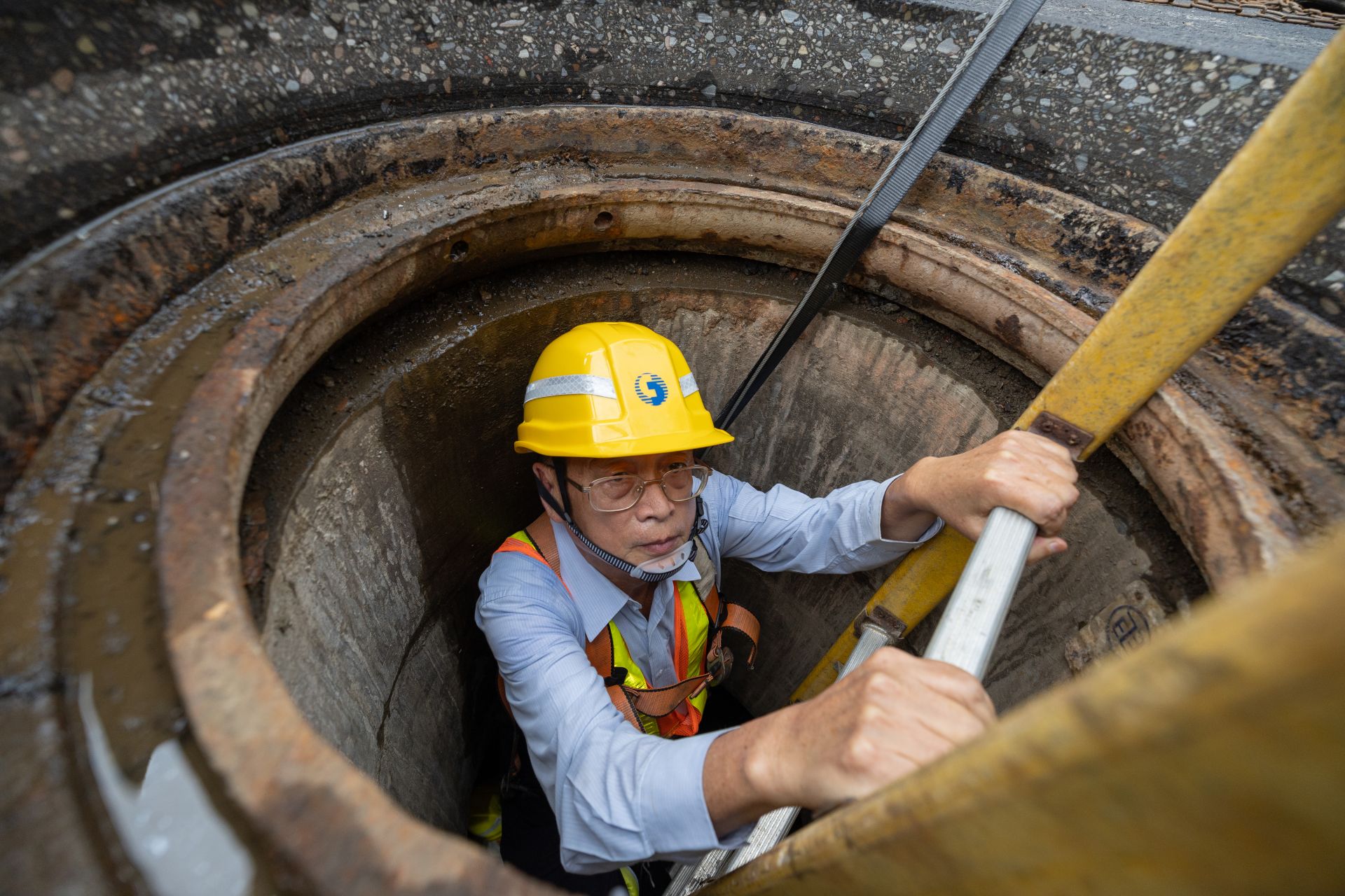 中華電信高雄營運處副總經理孫堂霖身著安全裝備，與同仁深入人孔管道維護著這道從臺灣通往全世界的橋梁已在中華電信服務46年，被同仁稱為「線路博士」。（文總提供）