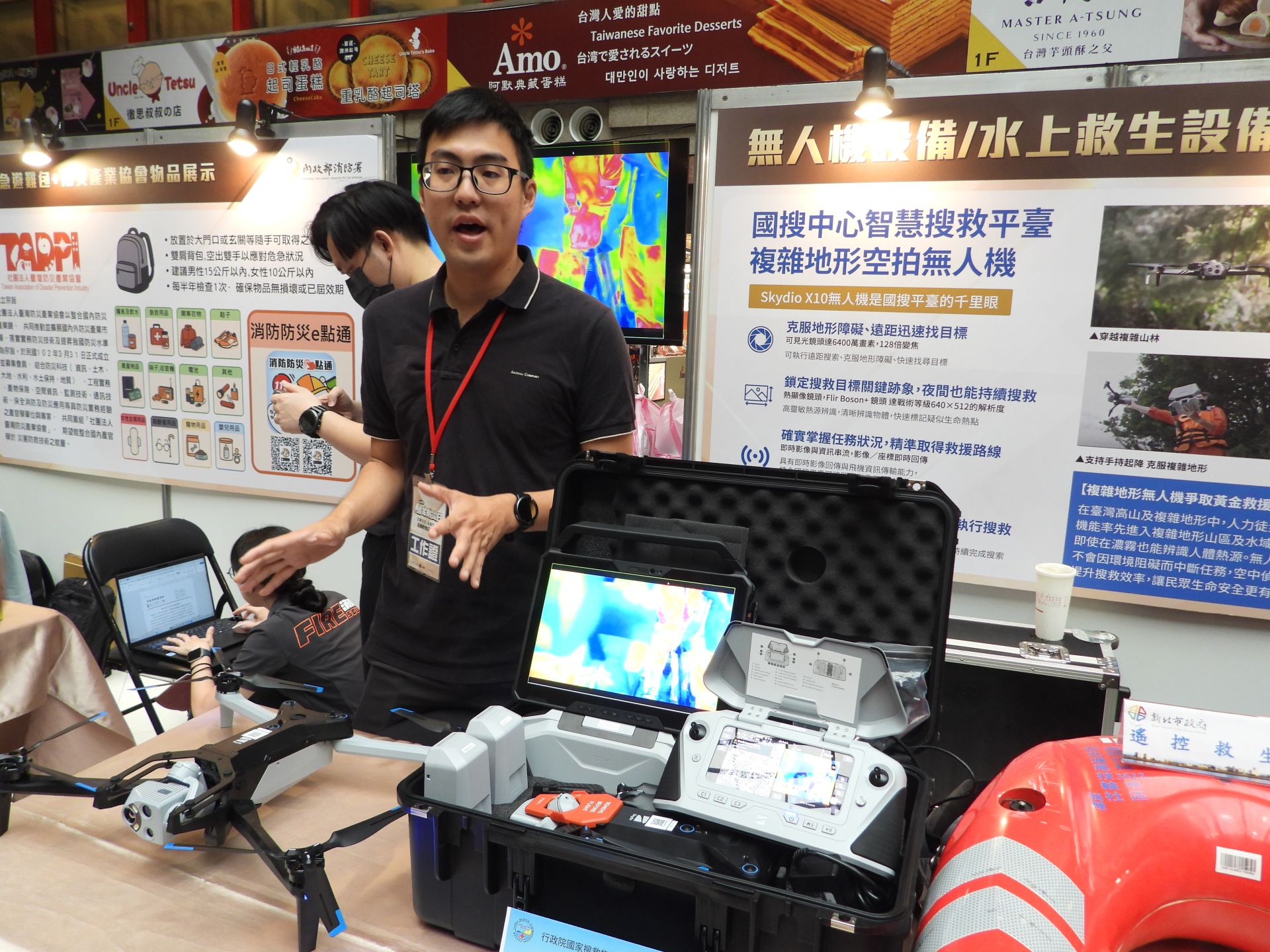 國搜中心無人機設備展示，說明無人機在拍照定位、吊掛運送等功能。（記者吳典叡攝）