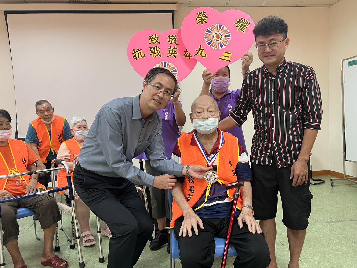 家主任李秦強代表輔導會頒發劉梅初爺爺抗戰紀念獎章，並邀請劉爺爺家人參與，一同分享榮耀和喜悅。（屏東榮家提供）