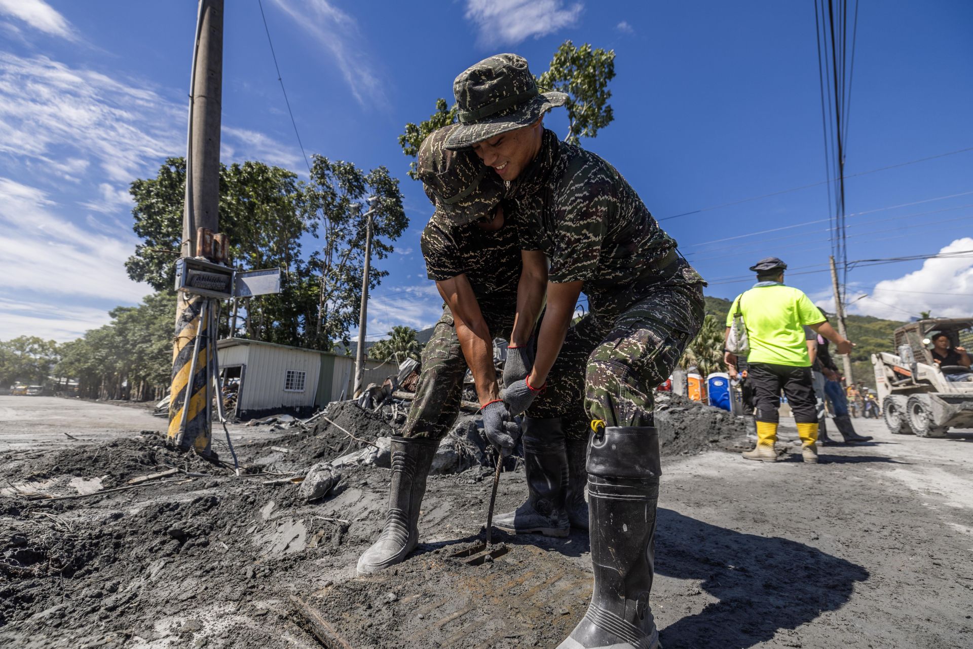  官兵合作打開堵塞水溝蓋，協助清理淤泥，暢通排水功能。（記者林睿奕攝）