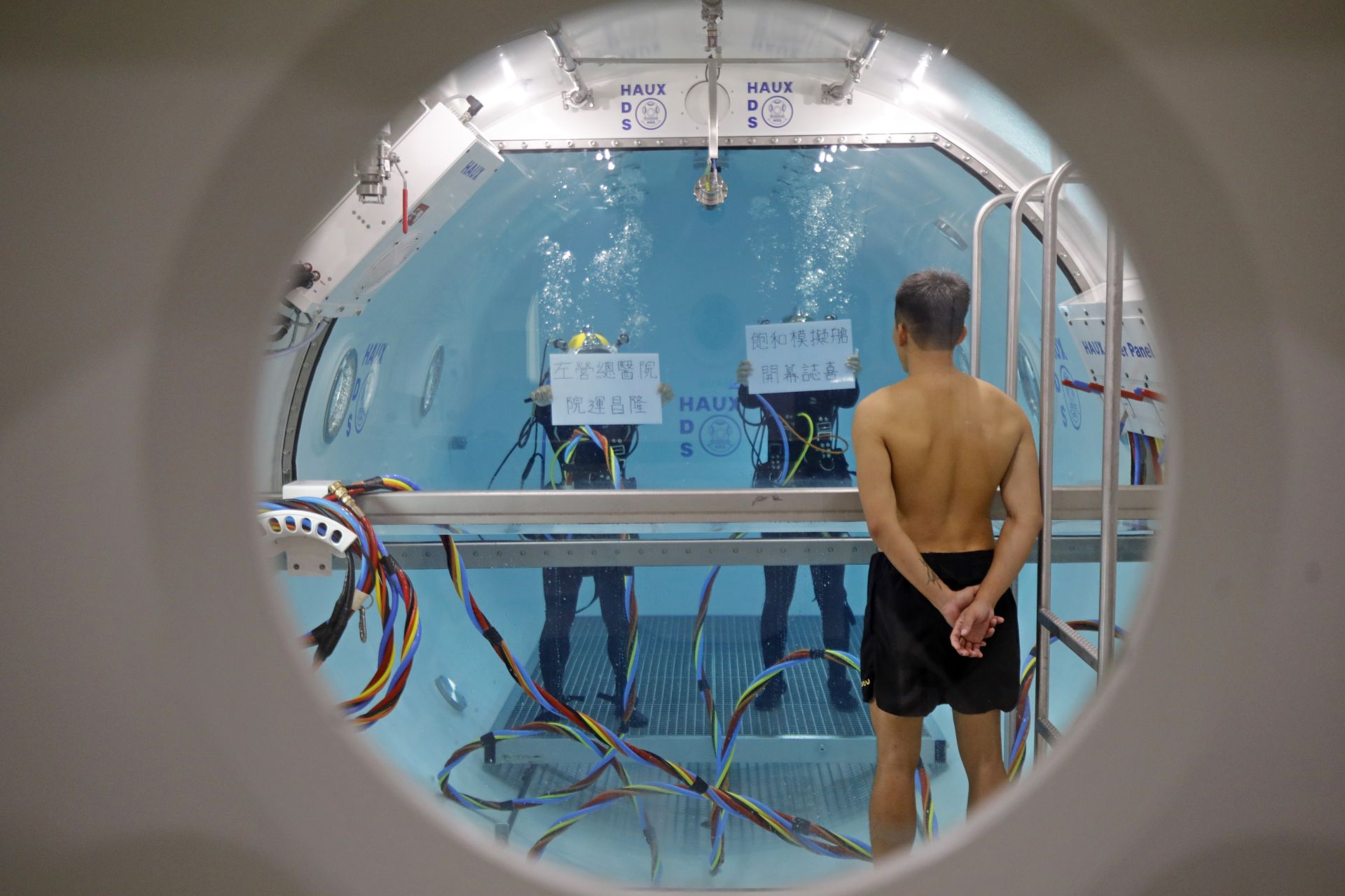 海軍水下作業大隊官兵在模擬飽和潛水訓練艙內進行動態操演，並以手牌祝賀左營總醫院潛水生理訓練中心啟用。（記者孫建屏攝）