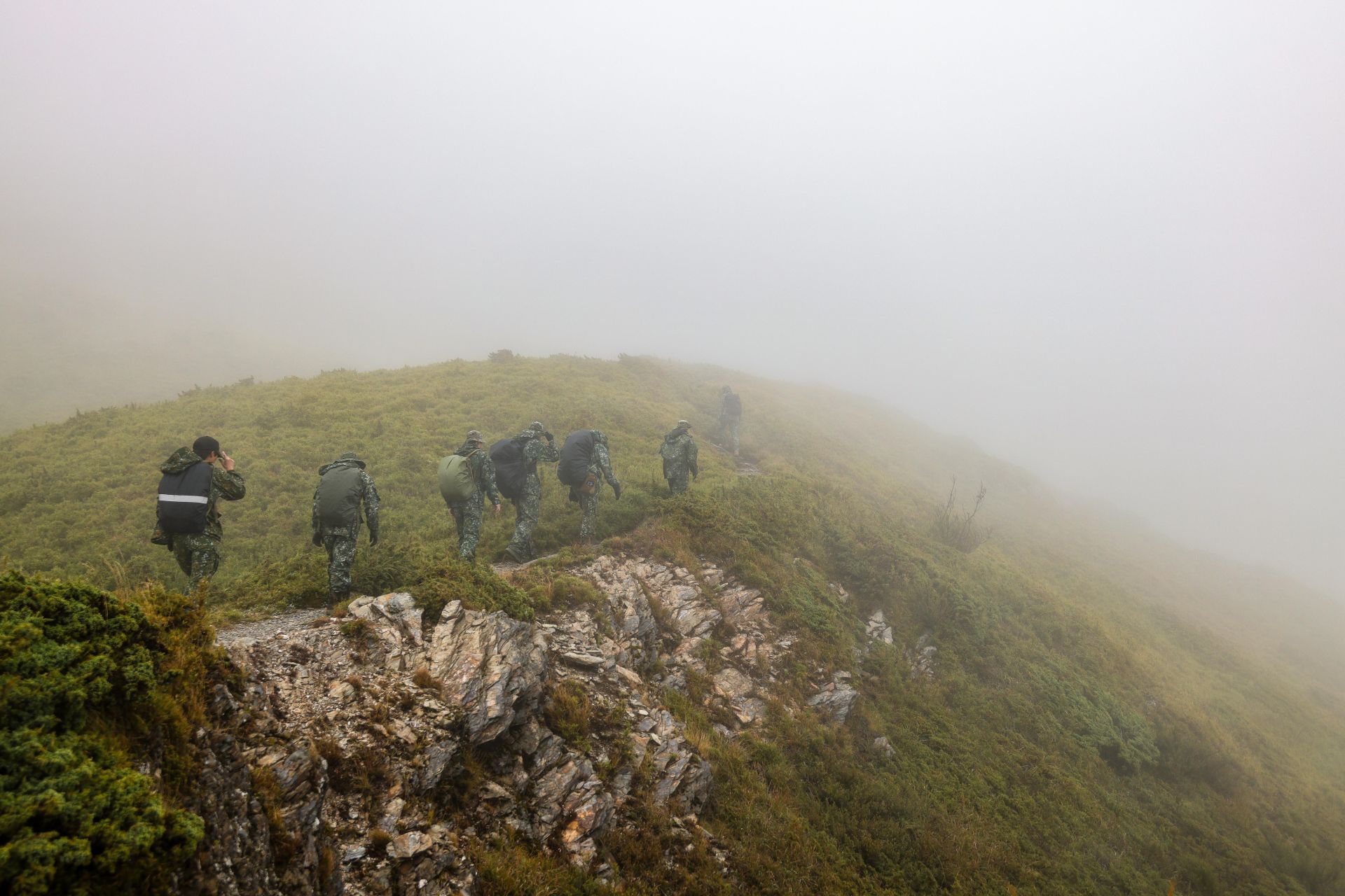  學員們頂著濃厚山霧與刺骨嚴寒風雨，在石門山北峰上展開傷患軌跡搜索行動。（記者王子昌攝）