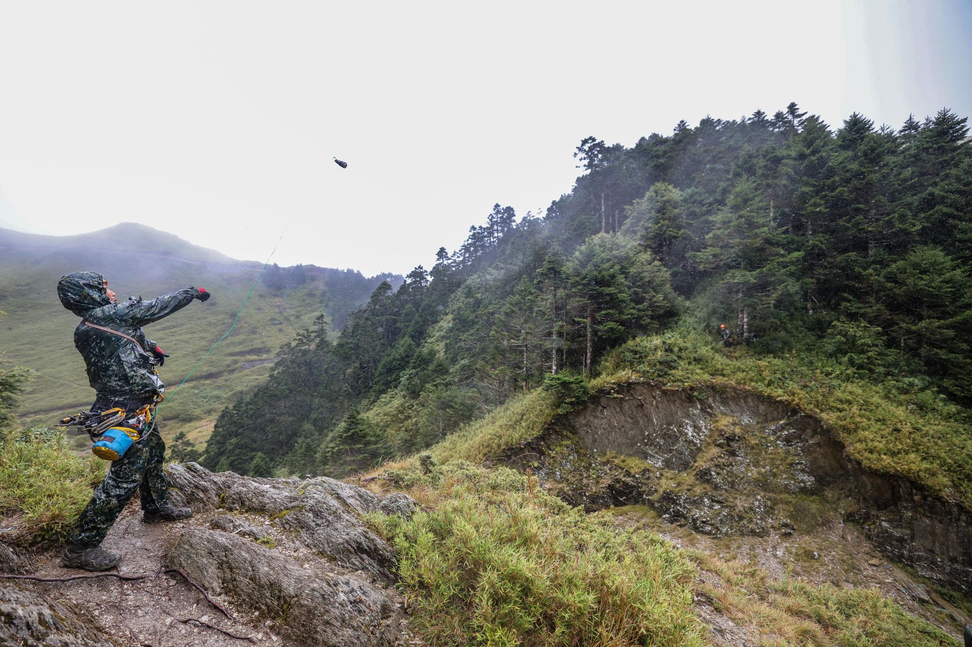 學員奮力擲出引線繩至峽谷對岸，以利先鋒手回送緊繃繩繫固兩側繩索系統。（記者王子昌攝）