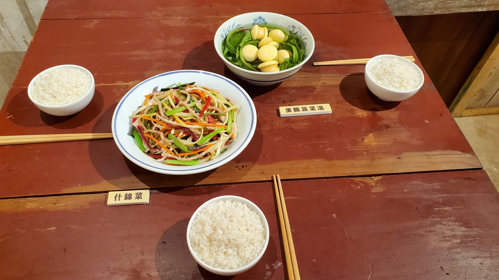 餐桌上以模型重現兩盤眷村菜，包括「蛋菇菠菜湯」和「什錦菜」。（記者黃朝琴攝）