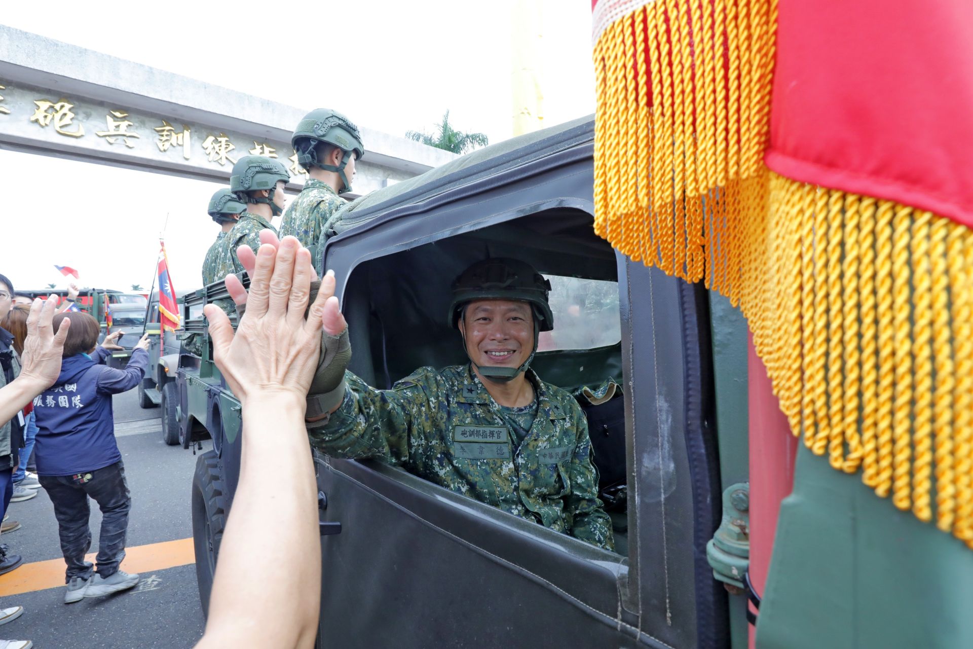 砲訓部機動車隊啟程前往關廟，民眾熱情與李指揮官擊掌道別。（記者孫建屏攝）
