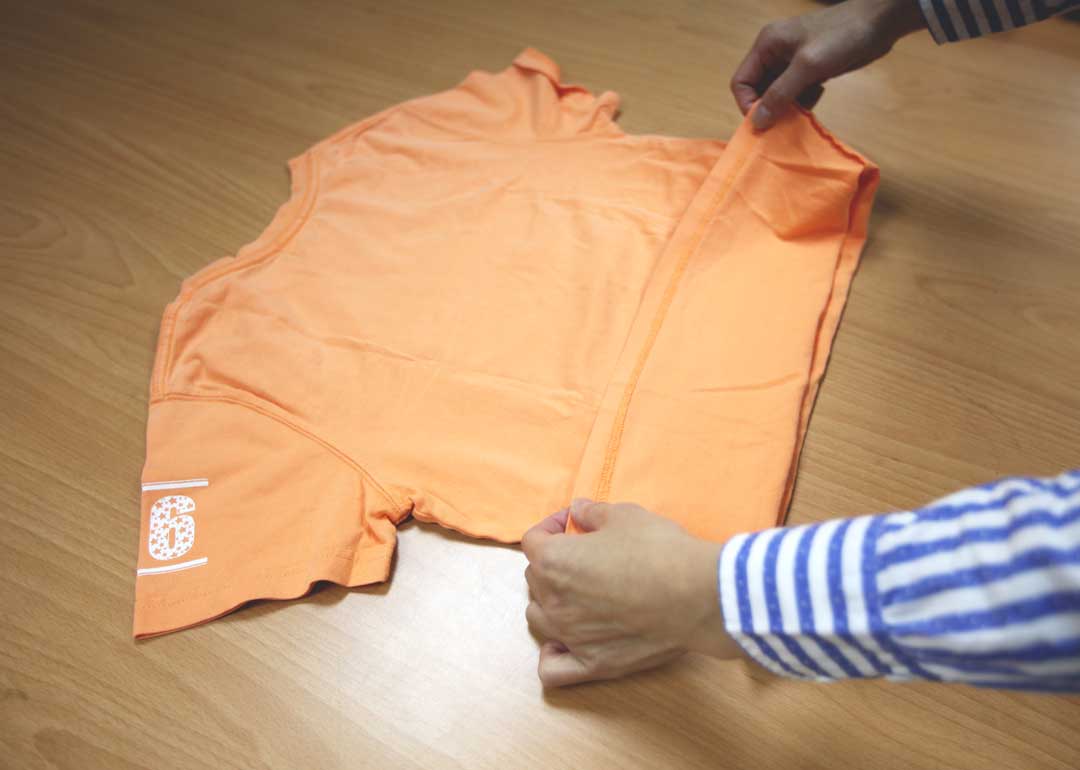 將衣服背面朝上攤平，下襬往上反摺1/3。