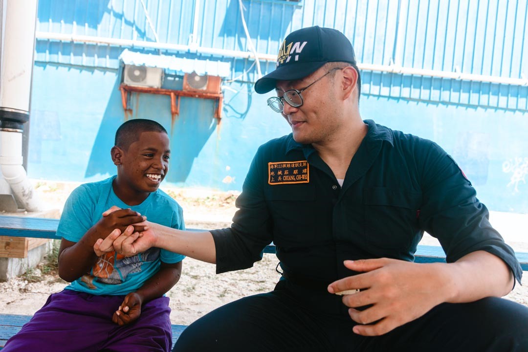 街上皮膚黝黑的小孩，親切地與官兵們擊掌、打招呼。