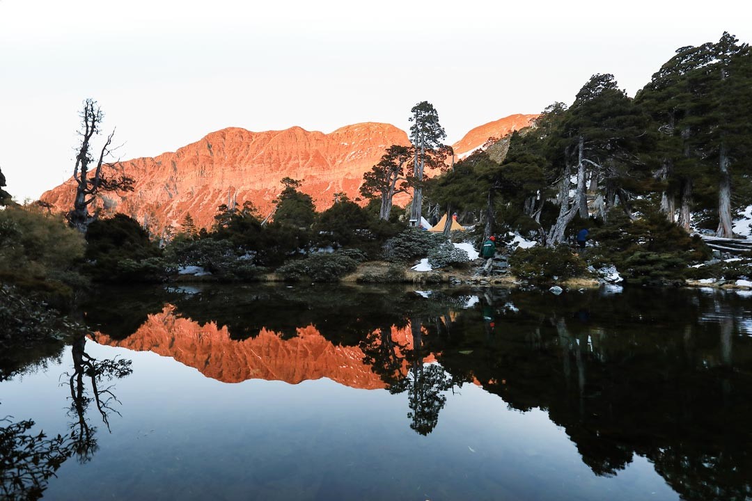 放晴的傍晚，夕陽將北稜角西壁染成一片火紅，映照在翠池無瑕的池面上。