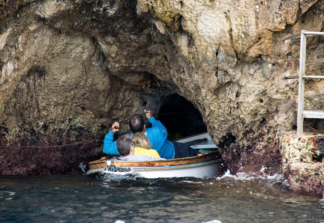 在洞口搭換另一艘更小的船，由船伕人力拉著海蝕洞邊的鐵鏈，然後借力拉滑入洞。